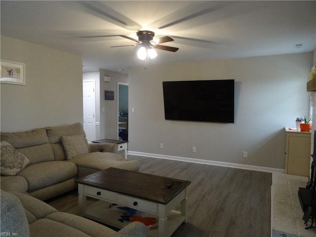 living room featuring ceiling fan, baseboards, and wood finished floors