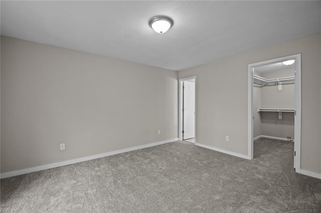 unfurnished bedroom with a walk in closet, baseboards, a closet, and carpet flooring