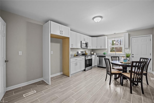 kitchen with white cabinets, visible vents, and stainless steel appliances