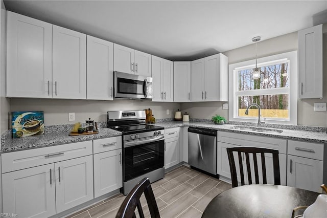 kitchen featuring white cabinets, appliances with stainless steel finishes, wood tiled floor, and a sink