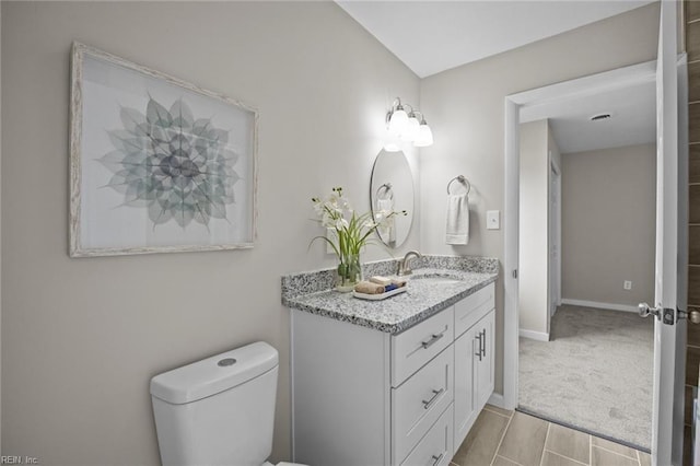 bathroom featuring toilet, vanity, and baseboards