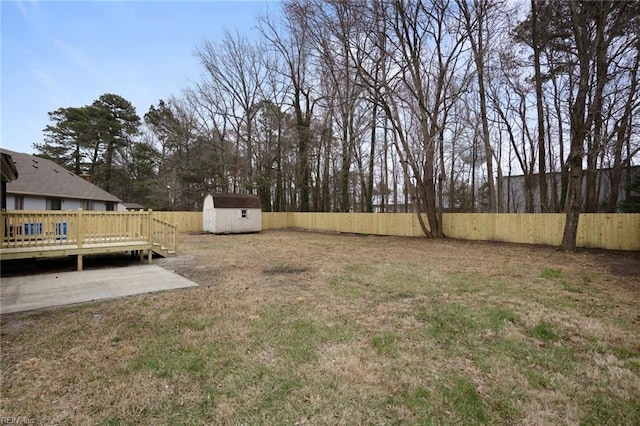 view of yard featuring a deck, an outbuilding, a storage unit, and a fenced backyard