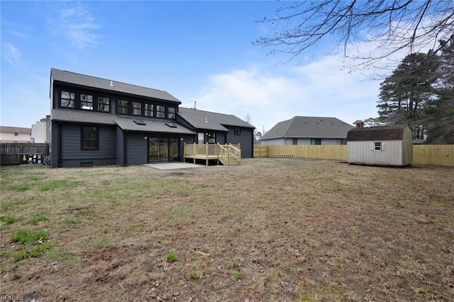 rear view of house with a shed, a yard, a fenced backyard, an outbuilding, and a deck