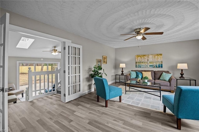 living room featuring a skylight, wood finished floors, and ceiling fan