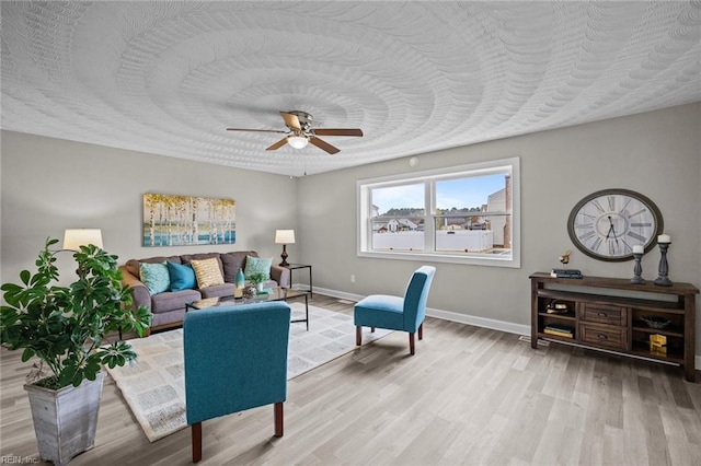 living area featuring ceiling fan, baseboards, a textured ceiling, and wood finished floors