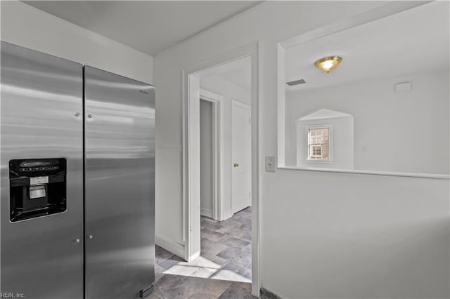 kitchen featuring visible vents, stainless steel refrigerator with ice dispenser, and stone finish floor