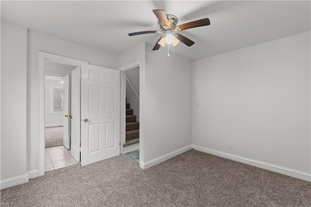 unfurnished room featuring light colored carpet, baseboards, and ceiling fan