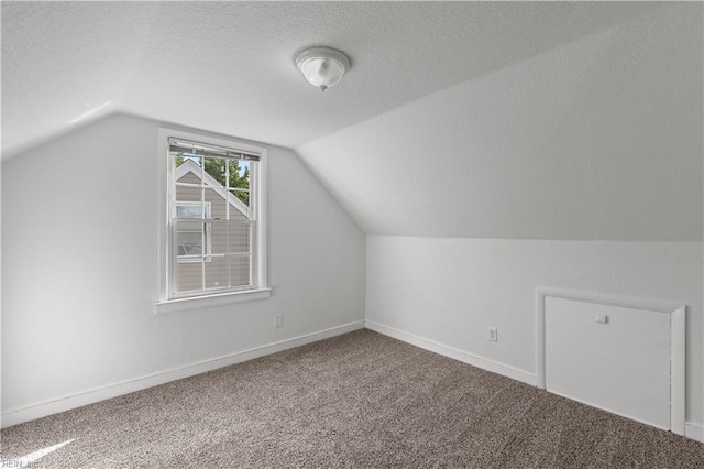 bonus room featuring baseboards, a textured ceiling, vaulted ceiling, and carpet