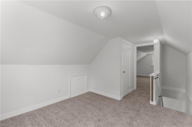 bonus room with vaulted ceiling, carpet, baseboards, and a textured ceiling