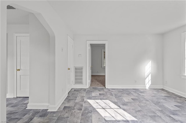 spare room featuring visible vents, arched walkways, and baseboards