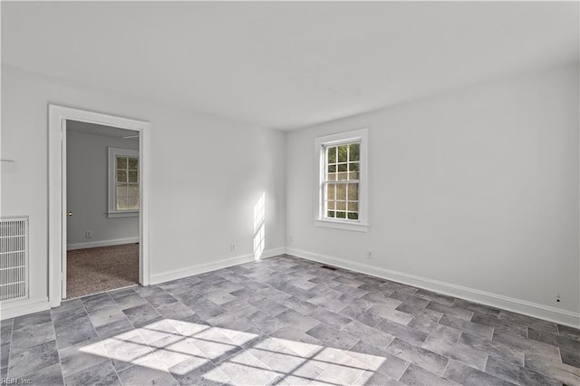 unfurnished room with visible vents, baseboards, and stone finish floor