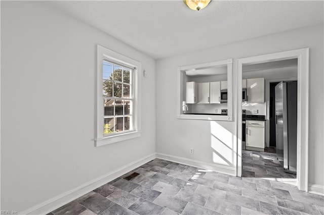 spare room featuring baseboards and stone finish flooring