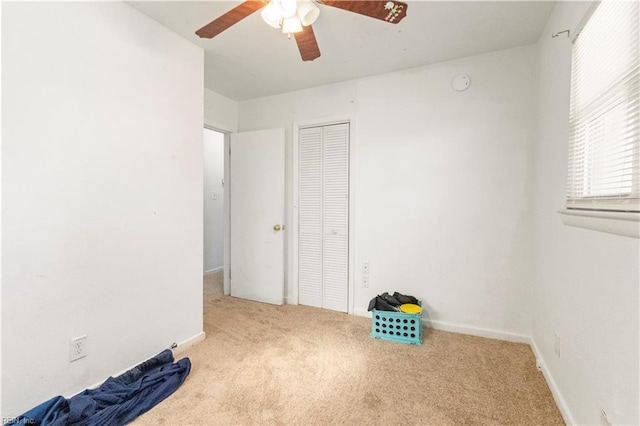 unfurnished bedroom featuring ceiling fan, carpet, a closet, and baseboards