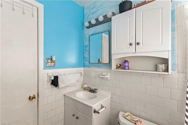 bathroom featuring vanity, tile walls, toilet, and a wainscoted wall