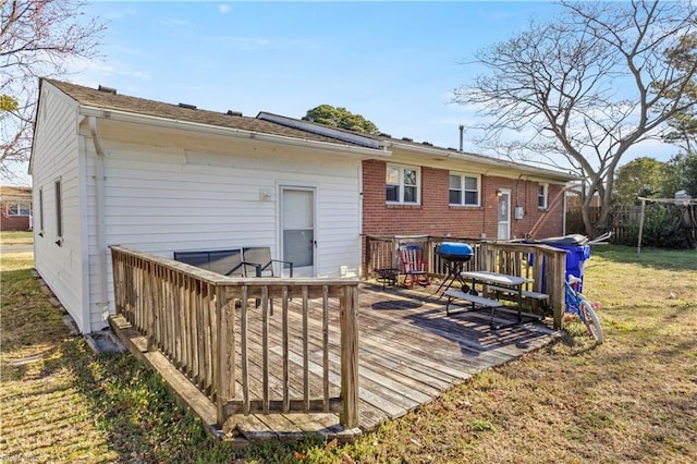 back of house featuring brick siding, a lawn, and a wooden deck