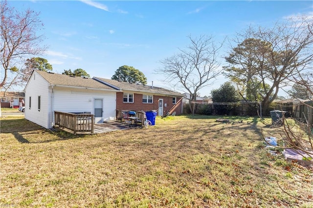 rear view of house featuring a lawn and fence