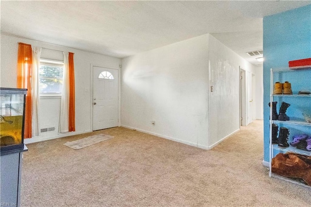 foyer with a textured ceiling, carpet, visible vents, and baseboards