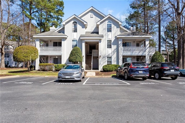 view of front facade featuring stairs, uncovered parking, and a chimney