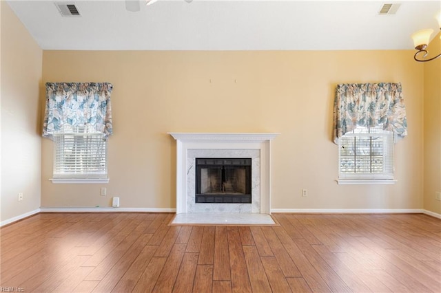 unfurnished living room with wood finished floors, visible vents, and a high end fireplace