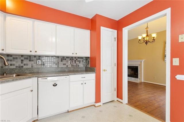 kitchen with a high end fireplace, a sink, white cabinets, and white dishwasher