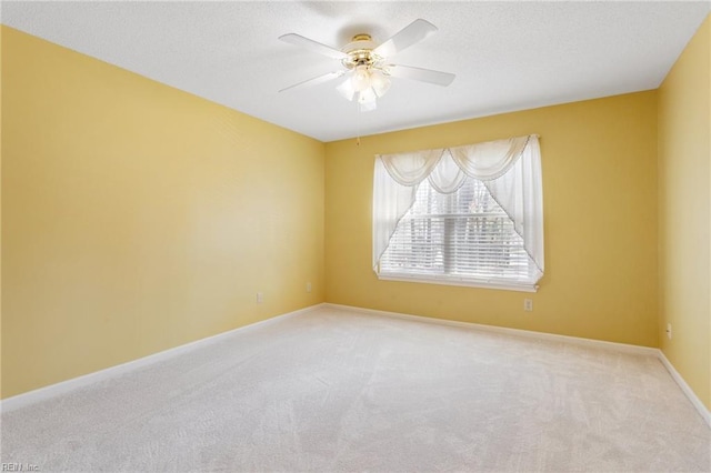 carpeted empty room with ceiling fan, a textured ceiling, and baseboards