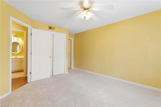 unfurnished bedroom featuring light carpet, visible vents, baseboards, and a closet