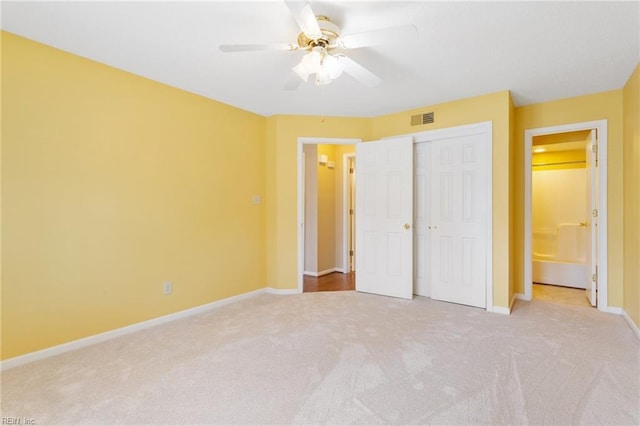 unfurnished bedroom featuring baseboards, visible vents, ensuite bath, a closet, and carpet flooring