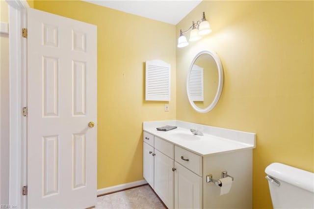 half bath with vanity, toilet, and baseboards