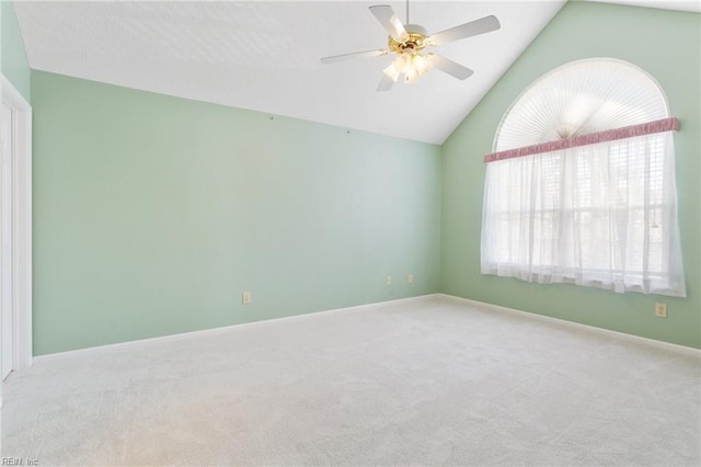 carpeted spare room featuring baseboards, a ceiling fan, and vaulted ceiling