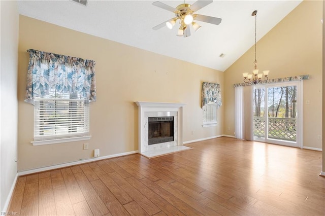 unfurnished living room with a wealth of natural light, wood finished floors, a fireplace, and ceiling fan with notable chandelier