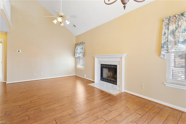 unfurnished living room with a fireplace, a ceiling fan, wood finished floors, and a healthy amount of sunlight