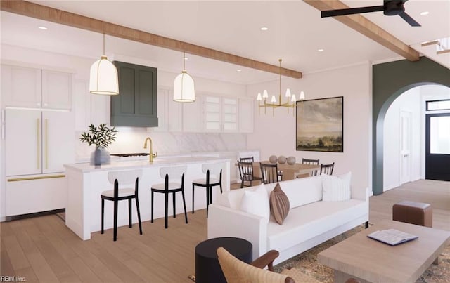 living area with beamed ceiling, recessed lighting, ceiling fan with notable chandelier, light wood-style floors, and arched walkways