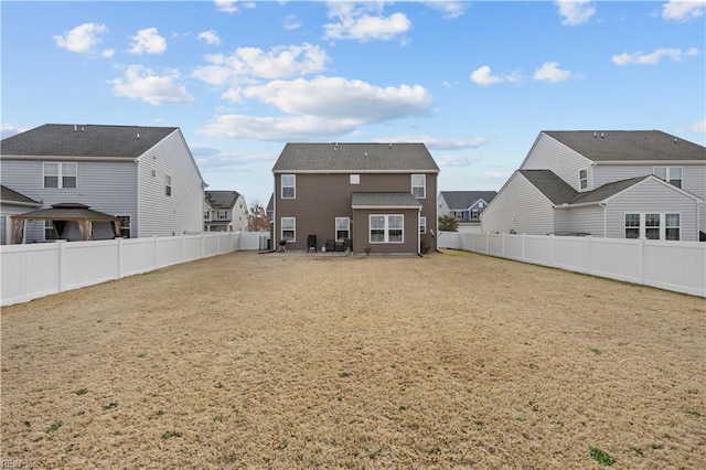 rear view of property featuring a yard, a residential view, and a fenced backyard