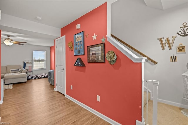 corridor featuring stairway, baseboards, and wood finished floors