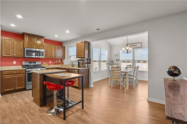 kitchen with visible vents, light wood-style flooring, stainless steel appliances, and an inviting chandelier