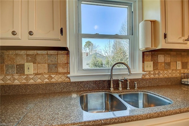 kitchen with a sink, backsplash, and dark countertops