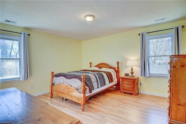 bedroom with light wood finished floors, visible vents, and baseboards