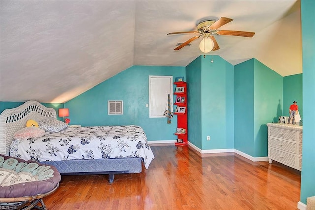 bedroom featuring visible vents, wood finished floors, baseboards, and lofted ceiling