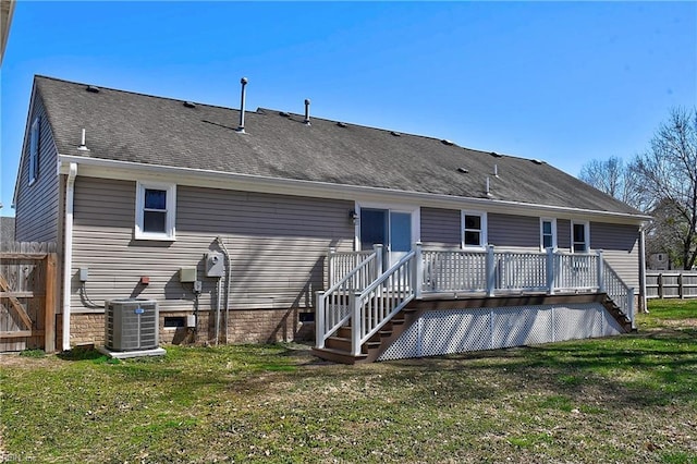 back of house featuring a lawn, a deck, fence, cooling unit, and roof with shingles