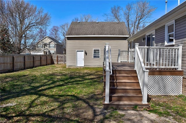 rear view of property featuring a yard, a wooden deck, a fenced backyard, and a shingled roof