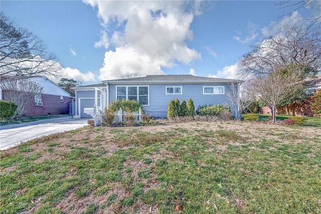 ranch-style house with an outbuilding, an attached garage, concrete driveway, and a front lawn