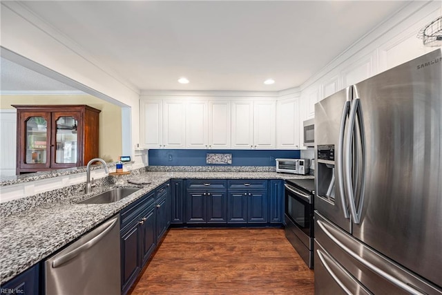 kitchen featuring a sink, light stone counters, blue cabinetry, dark wood-style floors, and appliances with stainless steel finishes