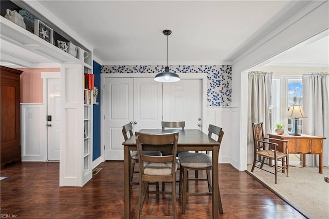 dining space featuring dark wood finished floors, crown molding, and wainscoting