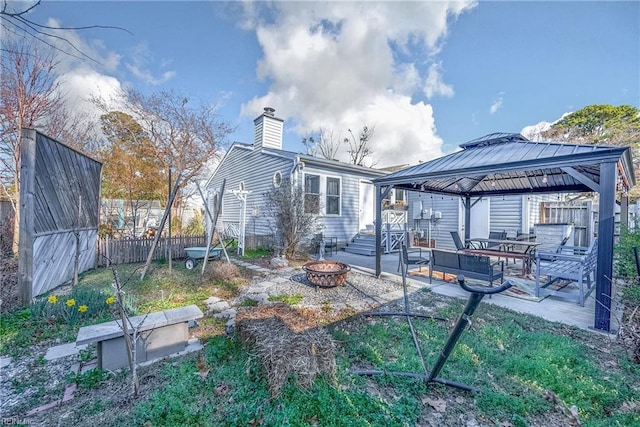 back of house with fence, a gazebo, a fire pit, a chimney, and a patio area