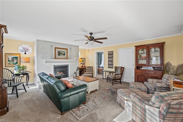 living area with a ceiling fan, ornamental molding, carpet, and a large fireplace