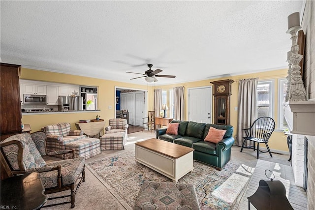 living area with baseboards, a fireplace, a textured ceiling, and ceiling fan