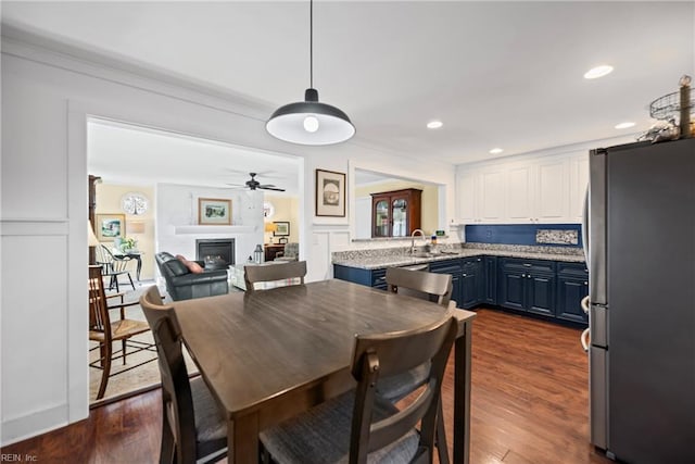 dining room with recessed lighting, dark wood-style flooring, a fireplace, and a decorative wall