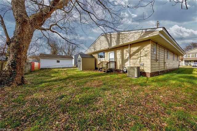 back of property featuring cooling unit, fence, a shed, a yard, and an outdoor structure