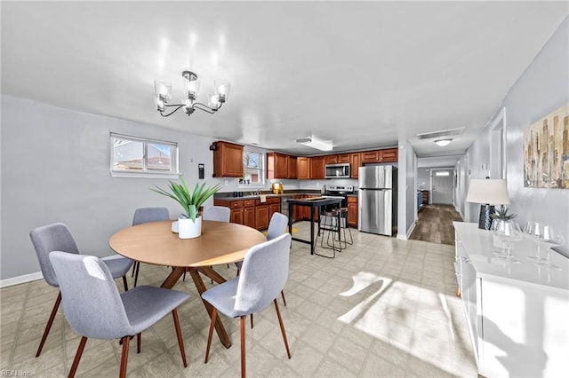 dining room featuring an inviting chandelier, light floors, visible vents, and baseboards