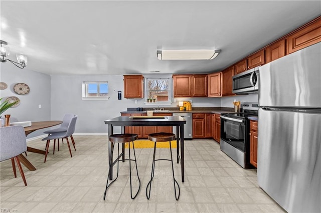 kitchen with dark countertops, a kitchen island, baseboards, light floors, and stainless steel appliances